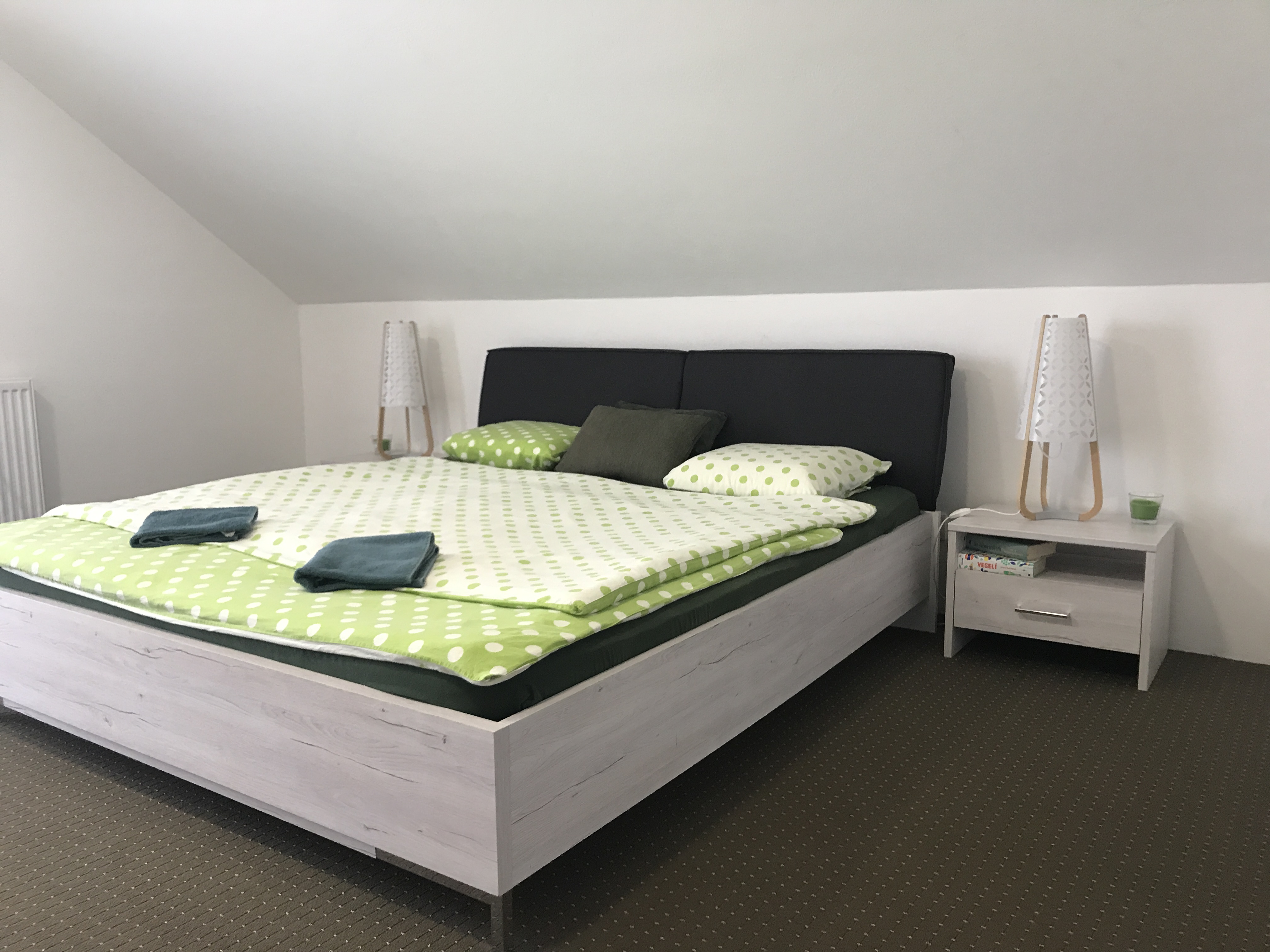 Interiér zeleného pokoje s manželskou postelí